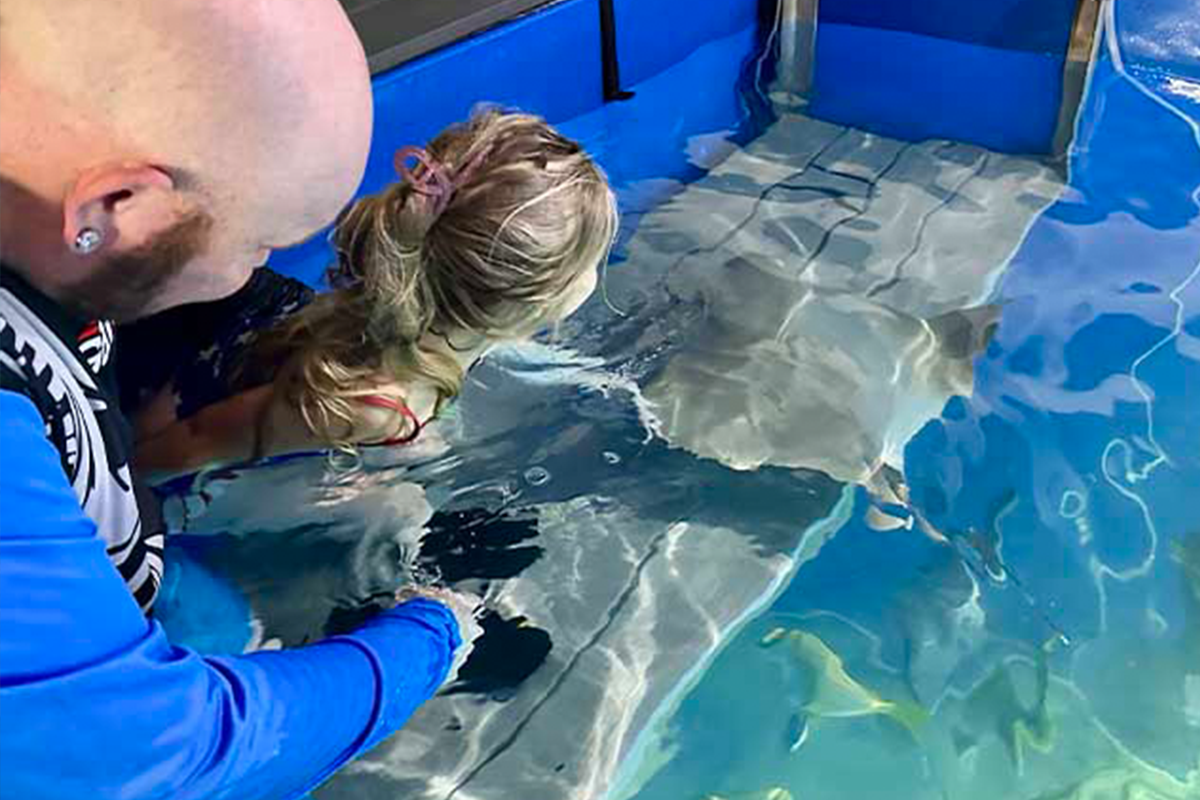 Family enjoying stingray encounter with aquarist guidance
